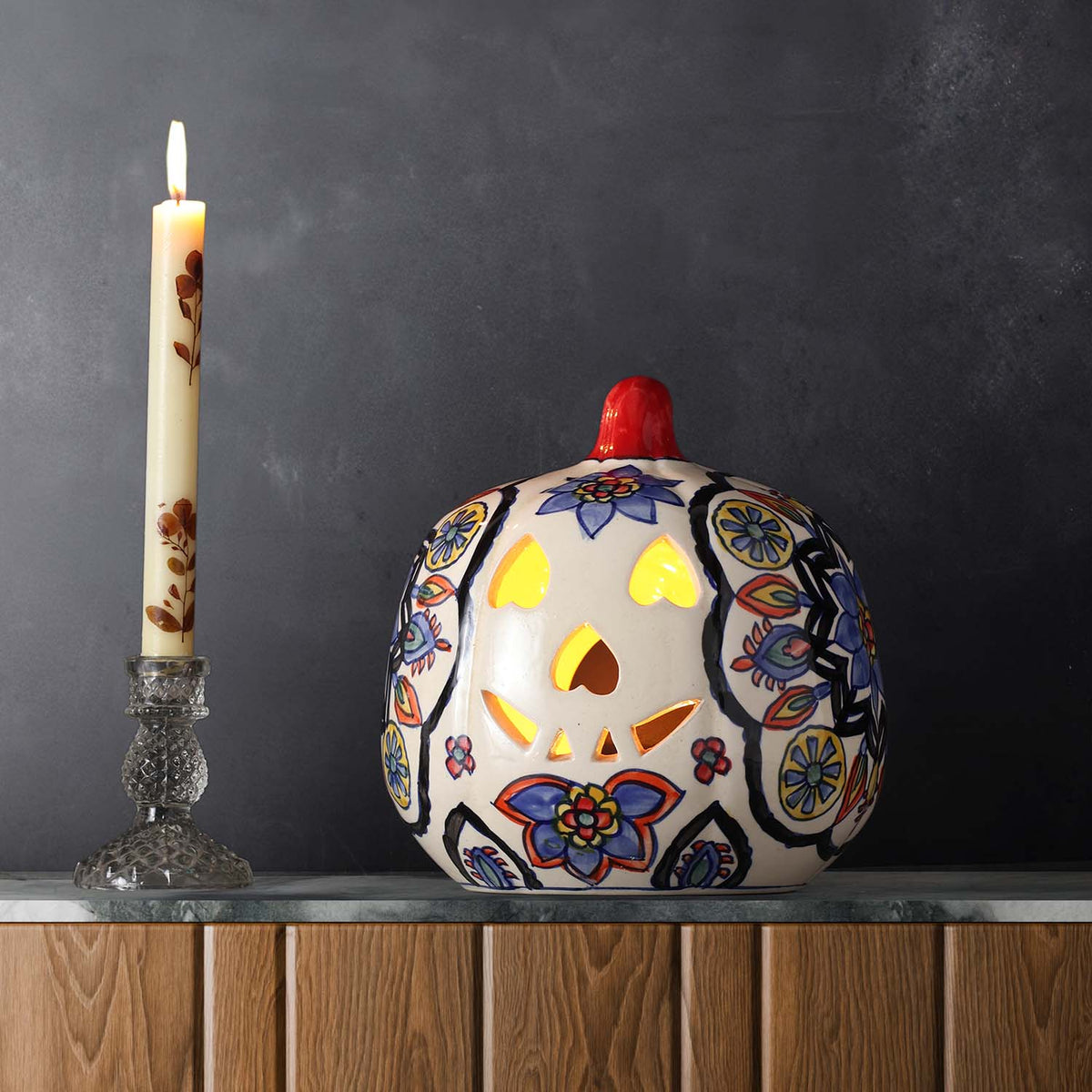 Multi-coloured floral ceramic pumpkin tea light holder styled on a console table creating a festive and decorative home setting