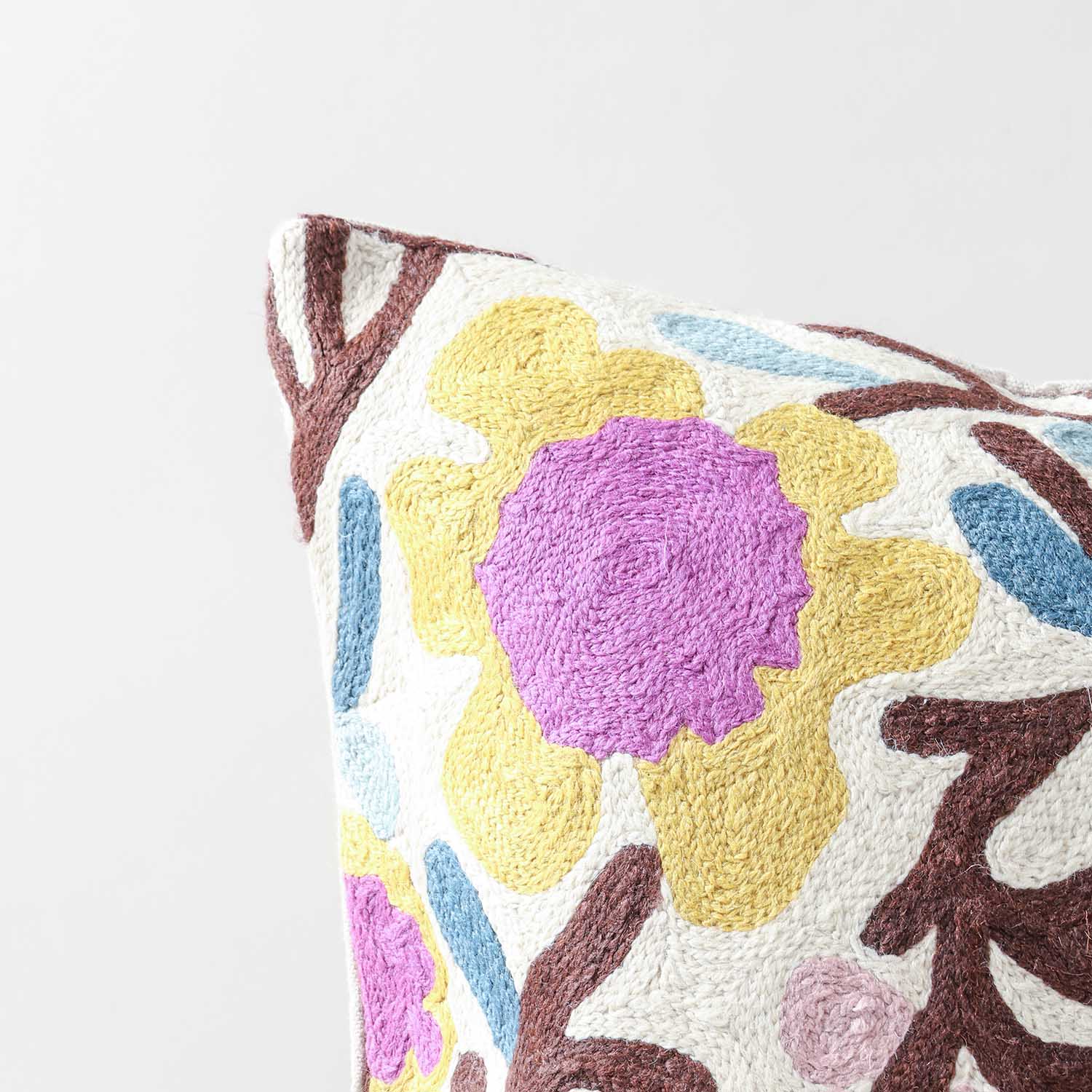 Close-up of floral tree crewel embroidery highlighting colourful blossoms, leaves and handcrafted wool stitching