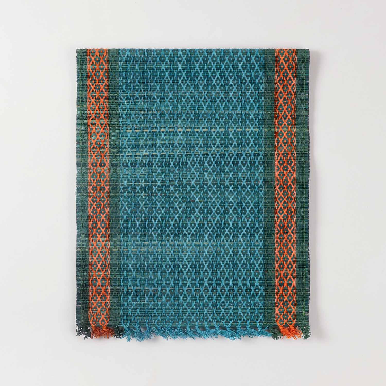 Folded blue Madhurkathi table runner crafted from natural river grass with handwoven texture and contrasting border details