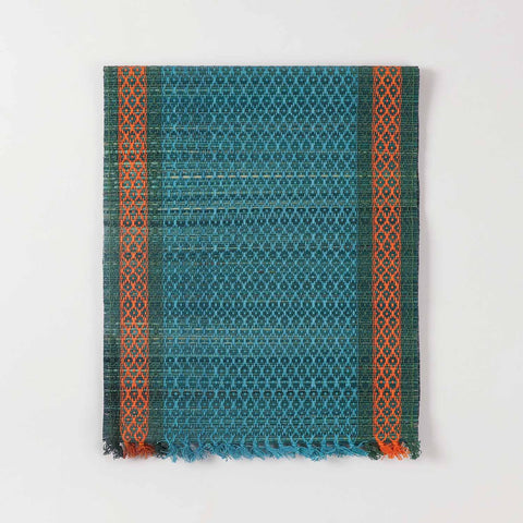 Folded blue Madhurkathi table runner crafted from natural river grass with handwoven texture and contrasting border details