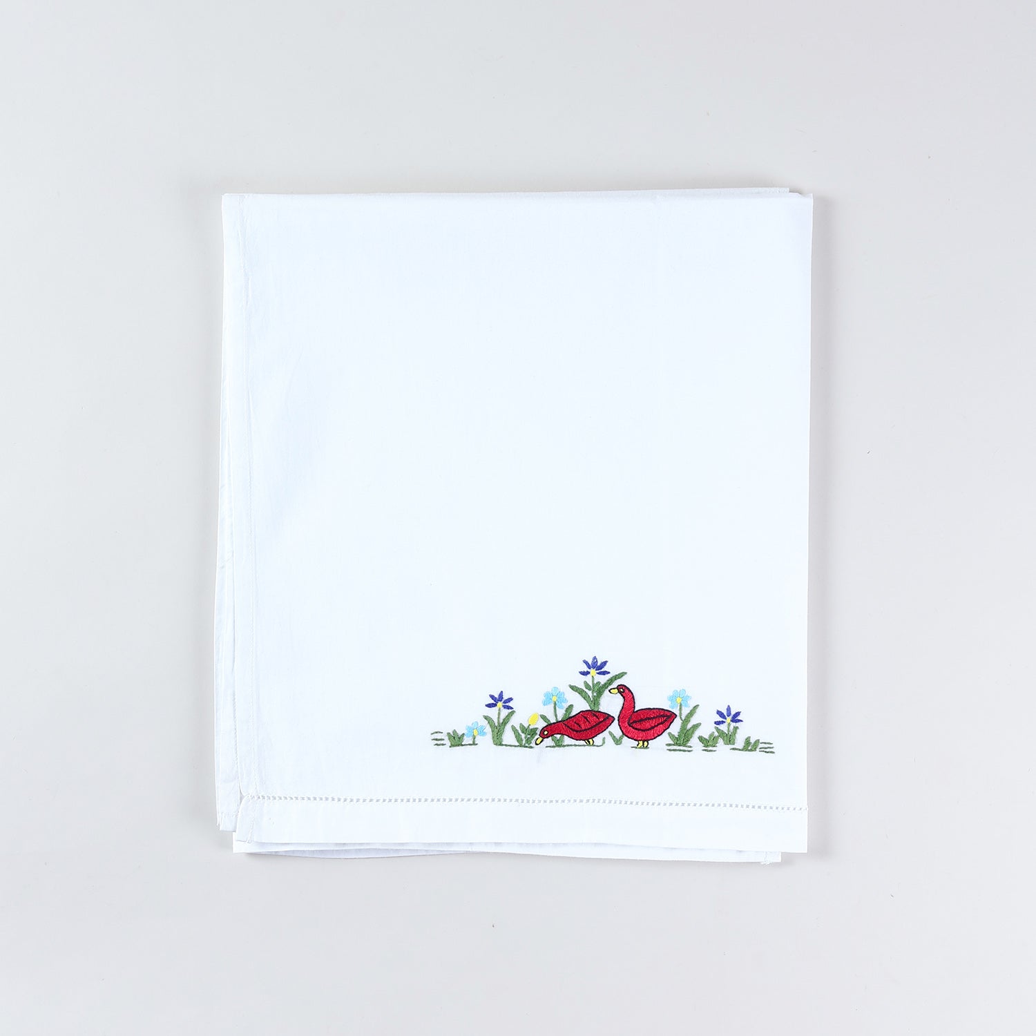 Neatly folded handmade cotton kids bed linen with Bengal Chikankari duck embroidery from the kids collection