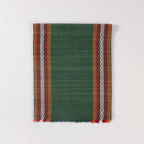 Folded green Madhurkathi table runner crafted from natural river grass with handwoven texture and contrasting border details