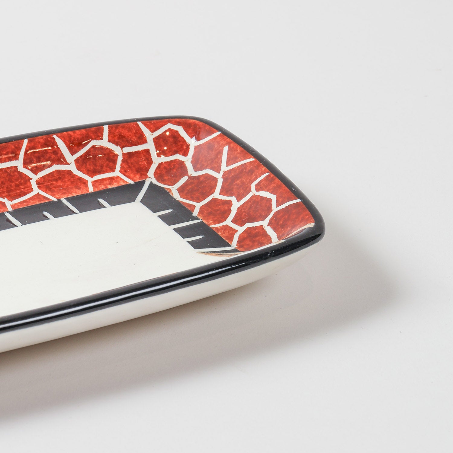 Close-up of a hand-painted giraffe motif on a ceramic serving platter, highlighting intricate African art and handcrafted detailing