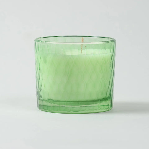 Eye-level view of a green apple scented soy wax candle showcasing the decorative chiseled glass design