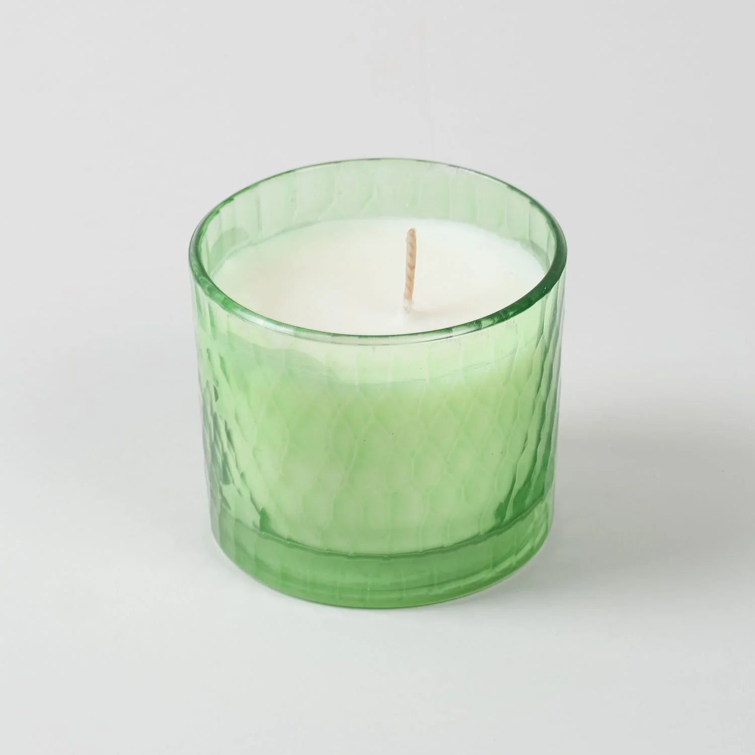 Front view of a green apple scented soy wax candle in a green chiseled glass holder