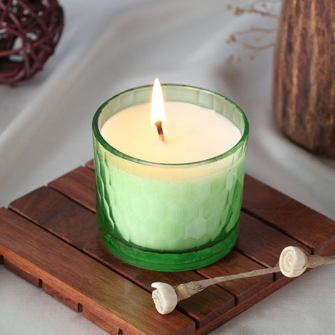 Green apple scented soy wax candle glowing warmly in a chiseled glass holder
