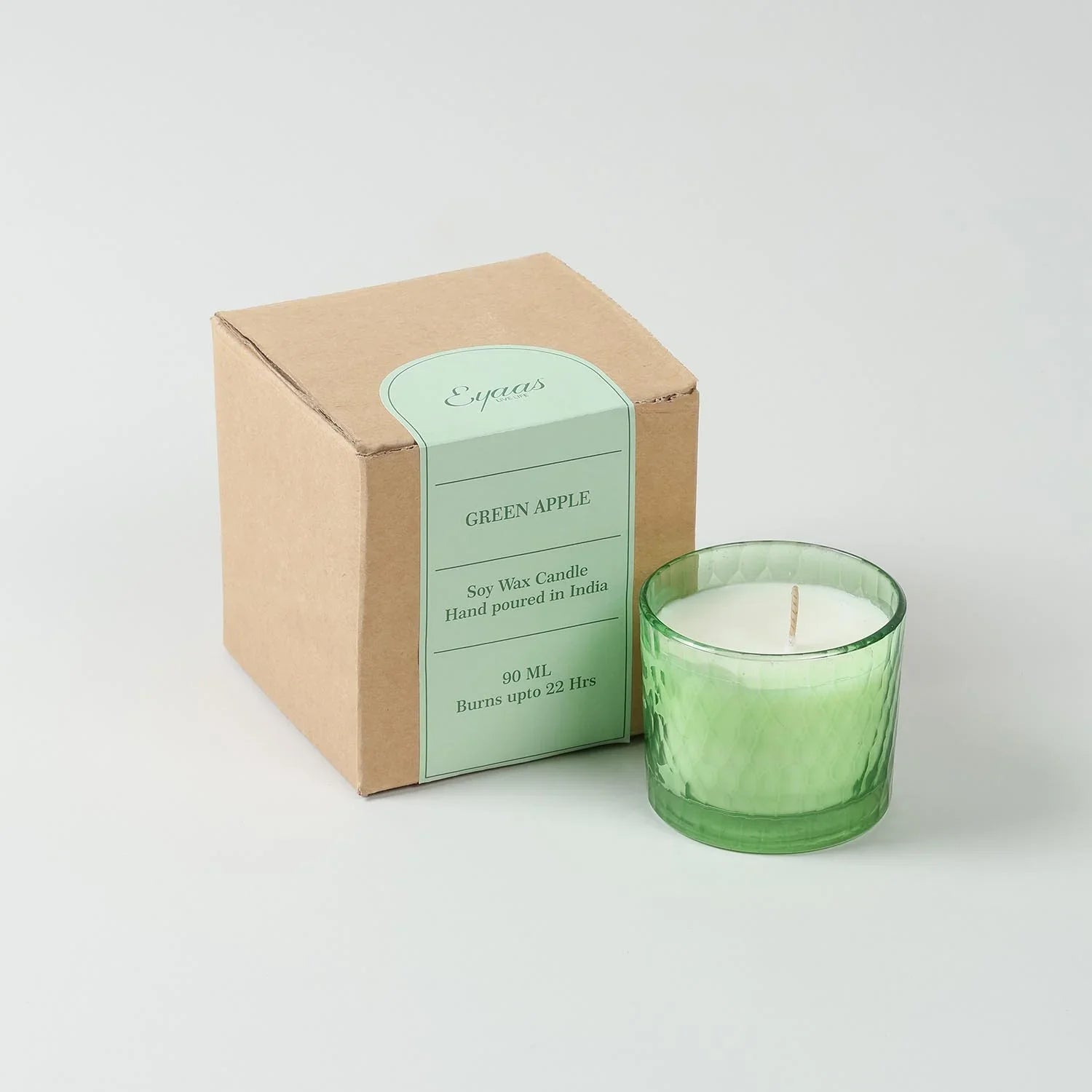 Green Apple scented soy wax candle in a decorative glass holder displayed alongside a gift
