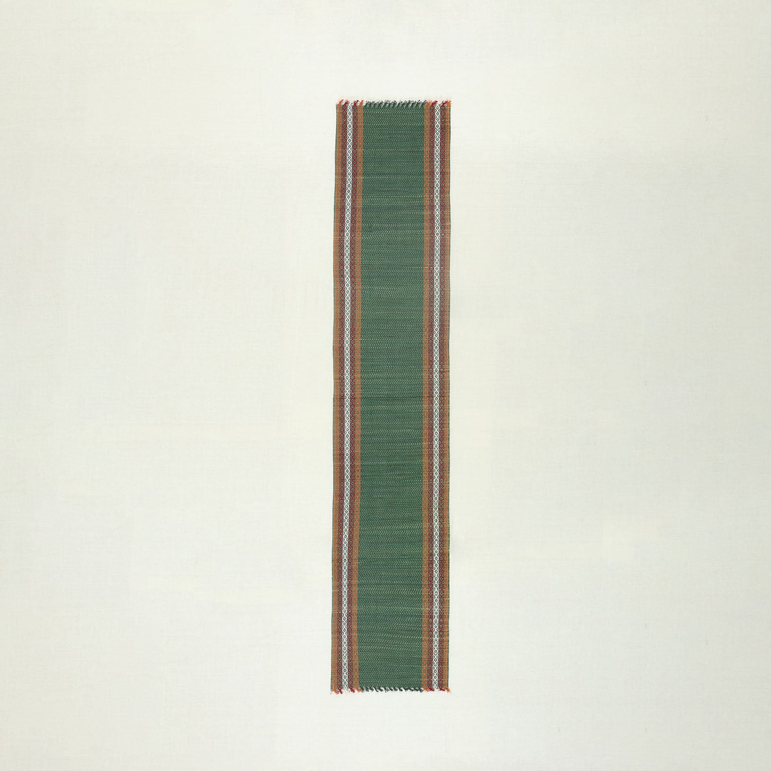 Full view of a handmade green Madurkathi table runner on a plain background, showcasing natural river grass weaving, colourful border accents, and handcrafted texture