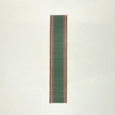Full view of a handmade green Madurkathi table runner on a plain background, showcasing natural river grass weaving, colourful border accents, and handcrafted texture