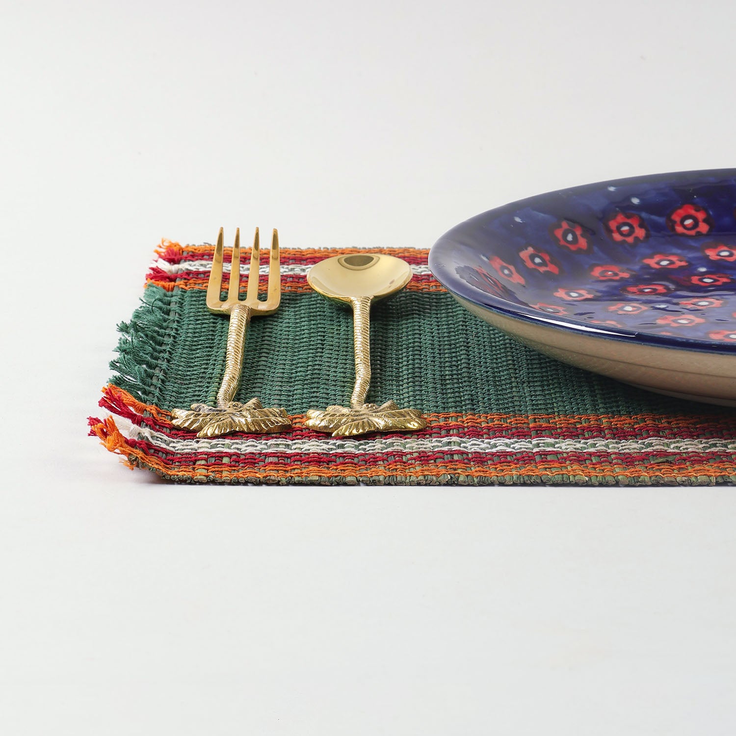 Handmade green Madhurkathi table mats styled on a dining table with cutlery and ceramic plates, creating an elegant table setting