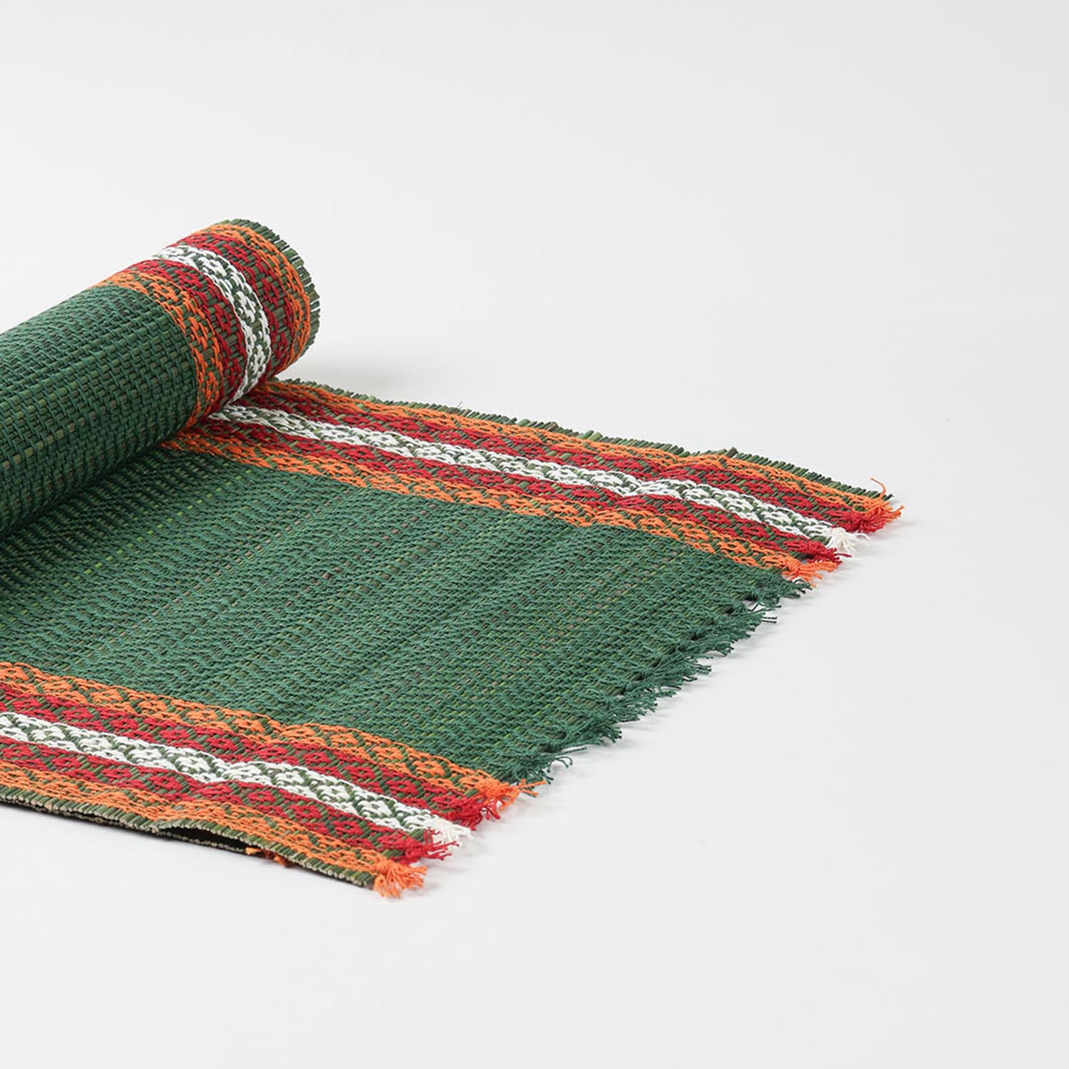 Angled view of a handmade green Madhurkathi table runner showcasing flexible natural fibre weaving and colourful woven borders