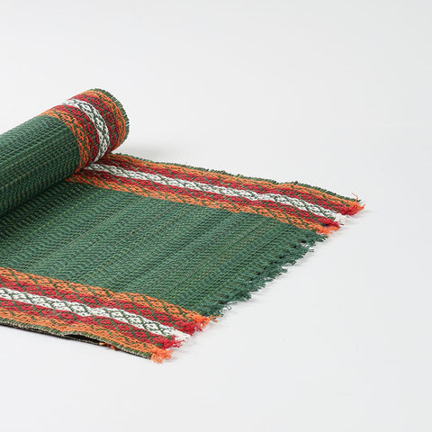 Angled view of a handmade green Madhurkathi table runner showcasing flexible natural fibre weaving and colourful woven borders