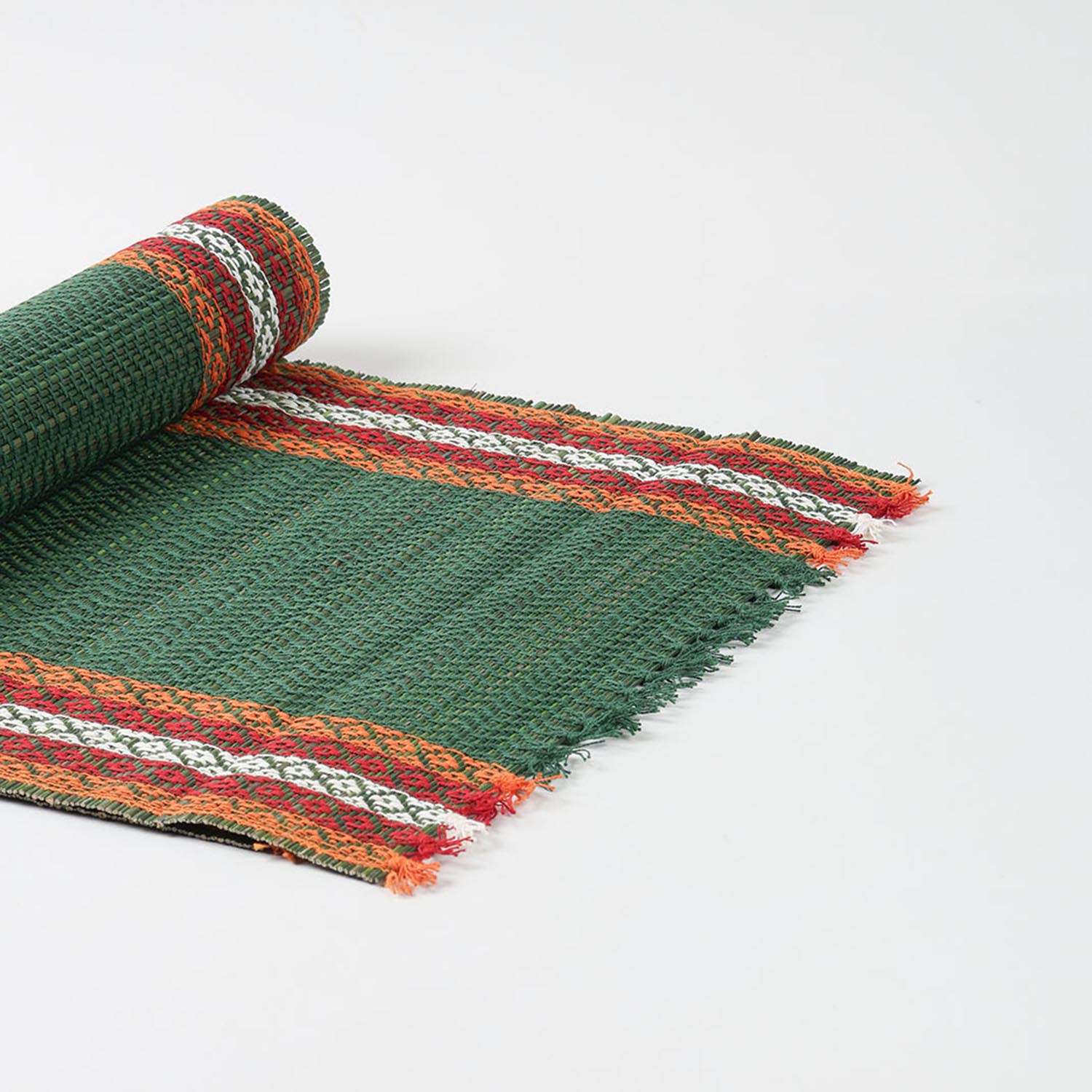 Angled view of a handmade green Madurkathi table runner highlighting flexible natural fibre weaving and colourful border accents