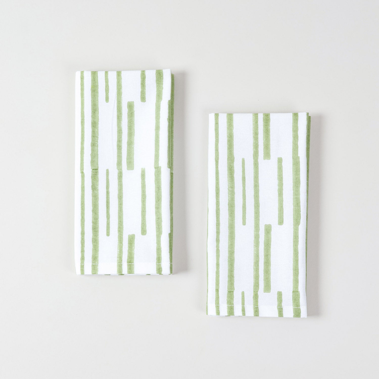 White and green cotton table napkins featuring hand printed stripe pattern for elegant place settings