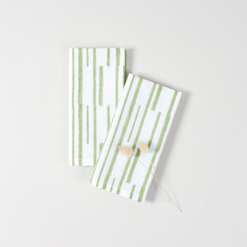 Green stripe cotton dinner napkins arranged with natural dried grass accents for modern table styling