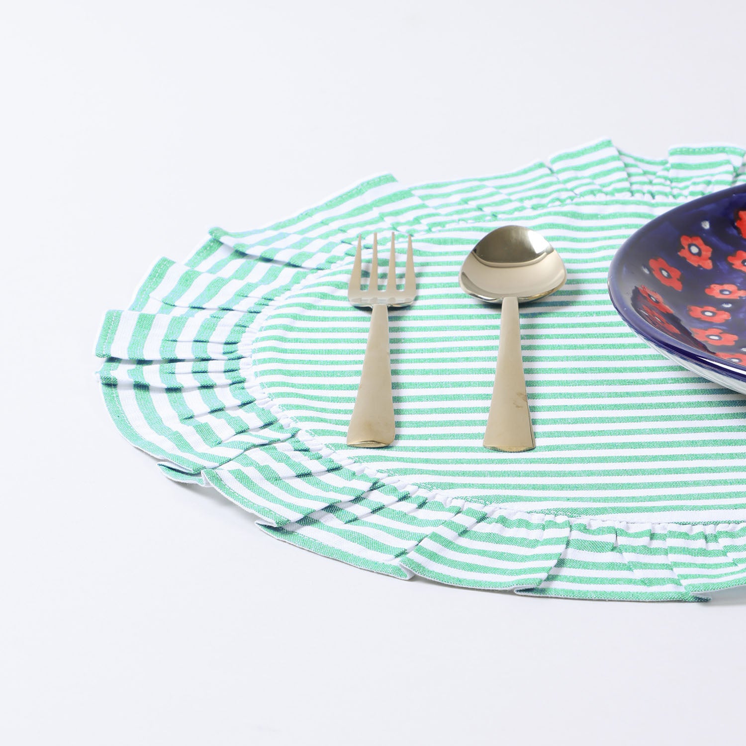 Handmade round cotton placemat with green stripes arranged with dinnerware on a dining table creating an elegant dining table décor setup