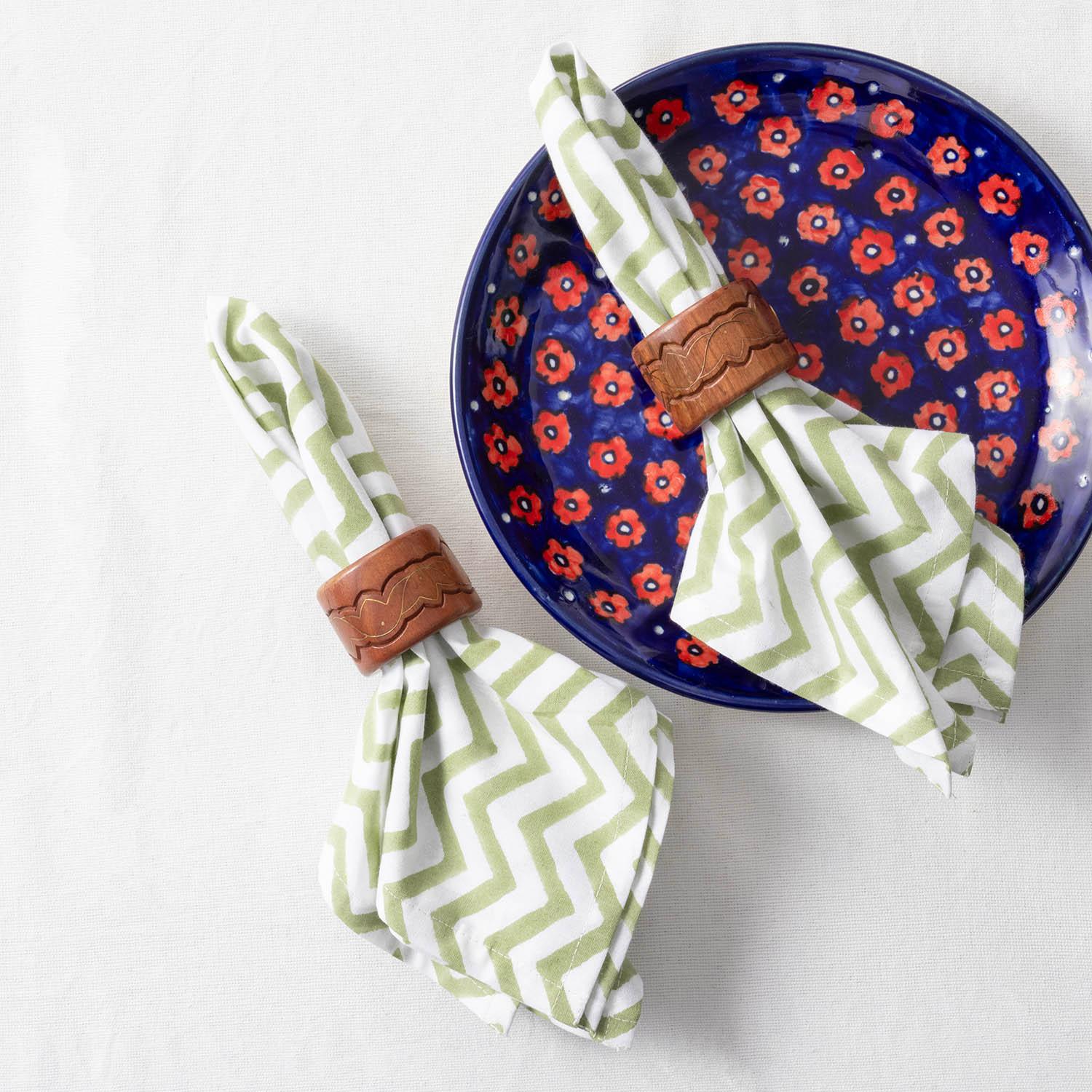 Green and white zigzag block printed cotton napkins styled on a dining table with tableware for an elegant table setting