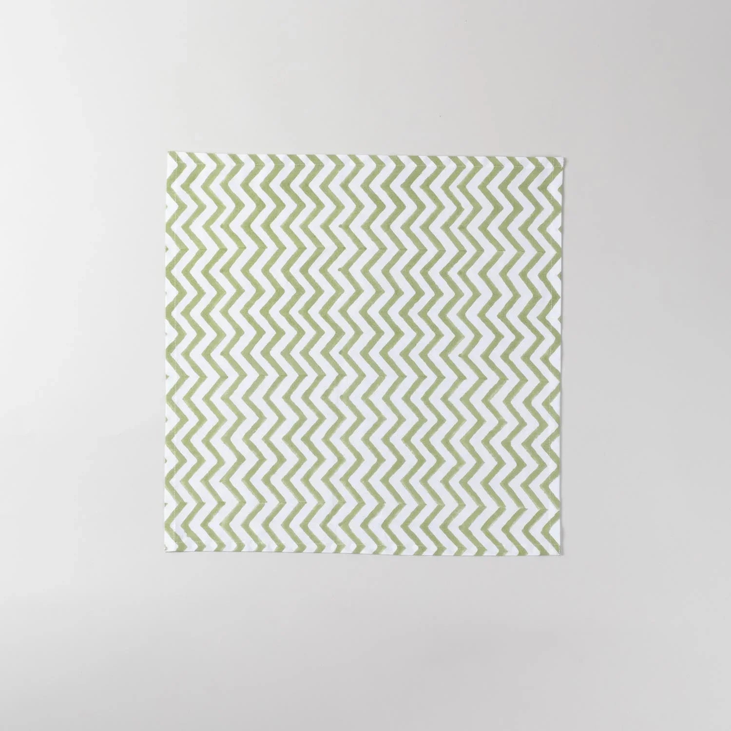 Full-size green and white zigzag block printed cotton napkin measuring 18 x 18 inches