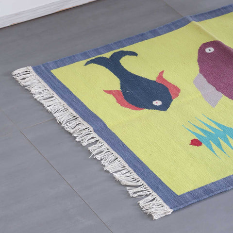 High-angled corner view of a handwoven cotton dhurrie featuring folk-inspired animal motifs and textured weave
