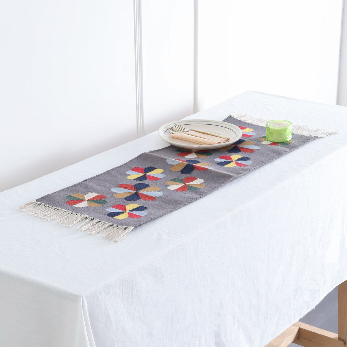 Grey handwoven cotton floor runner with colourful geometric floral motifs styled in a table  as a decorative home accent
