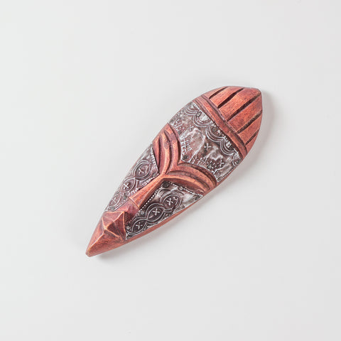 Angled view of a handcrafted African wooden mask showcasing decorative metalwork, carved features, and authentic African handicraft artistry