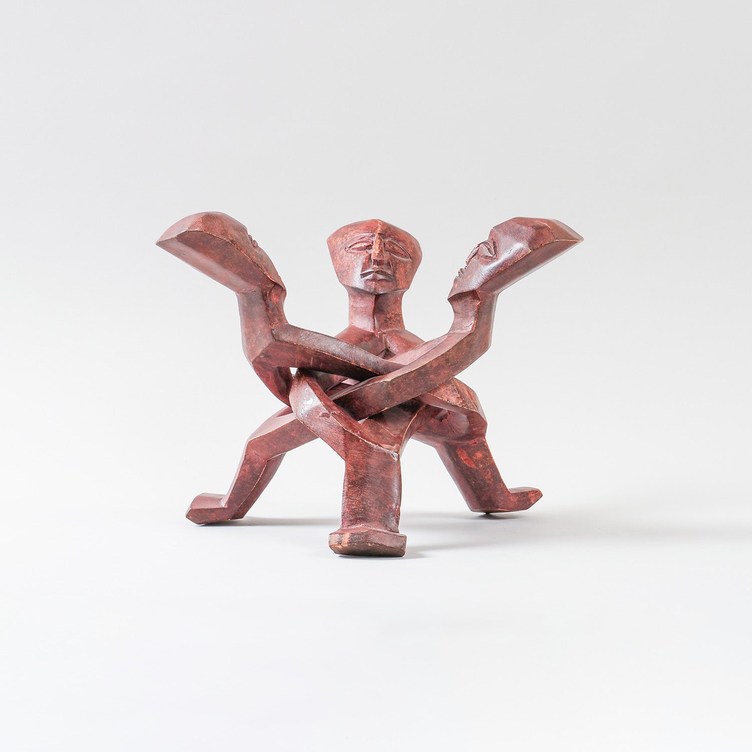 Hand-carved wooden stand featuring stylised human figures, designed to support a ceramic serving bowl while adding artistic appeal