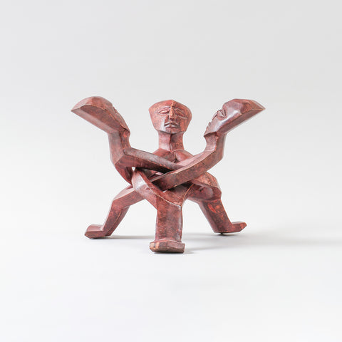 Hand-carved wooden stand featuring stylised human figures, designed to support a ceramic serving bowl while adding artistic appeal