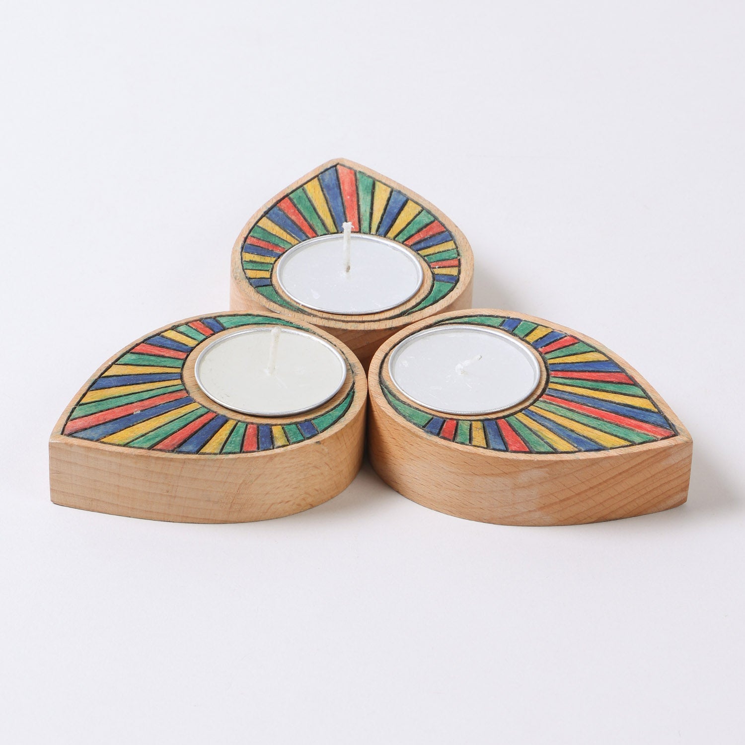 Set of three hand carved wooden t-light holders featuring rainbow colours and raindrop inspired shapes