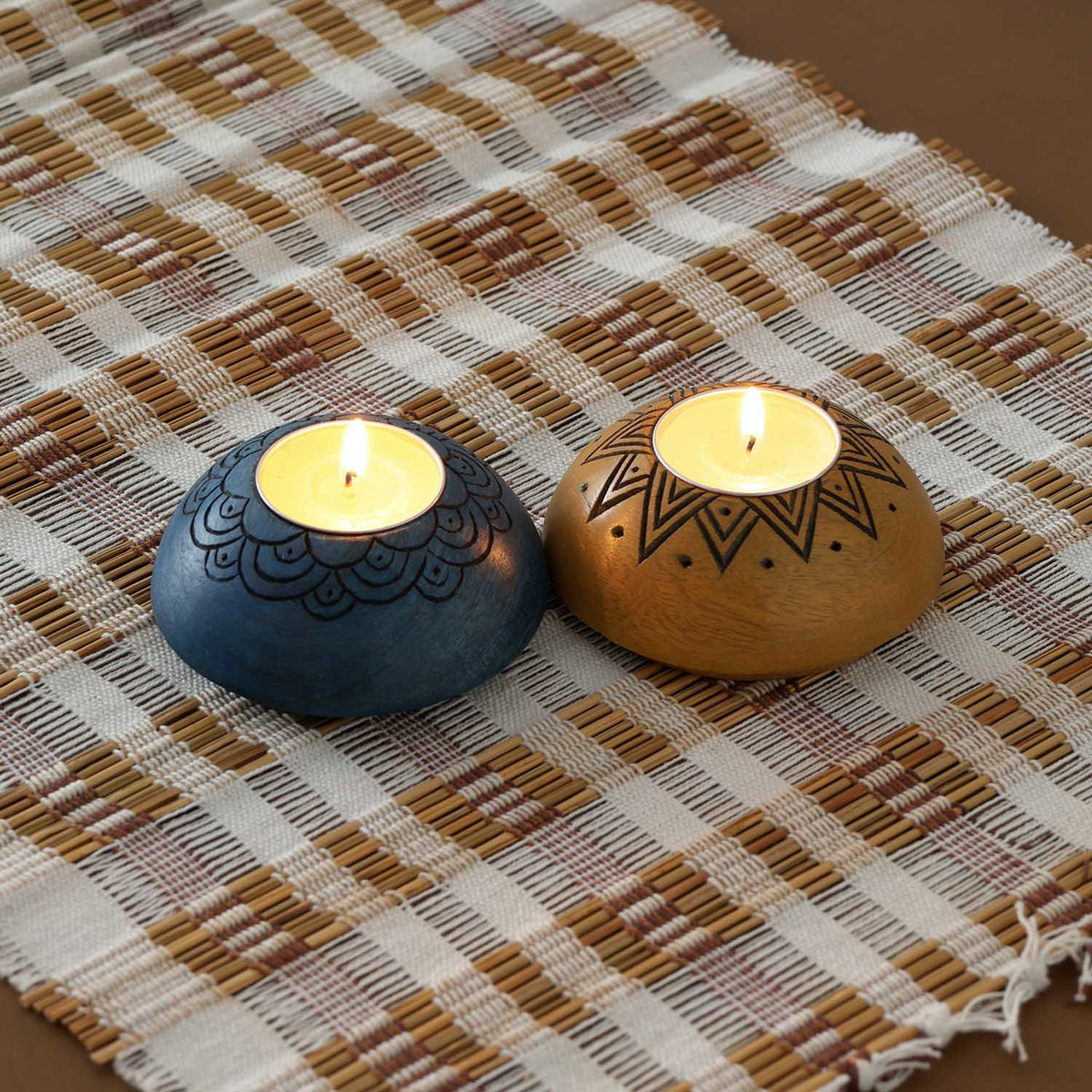 Handcarved wooden T-light holder set of 2 in blue and yellow displayed with lit tea lights, adding warmth to handmade decor and festive settings