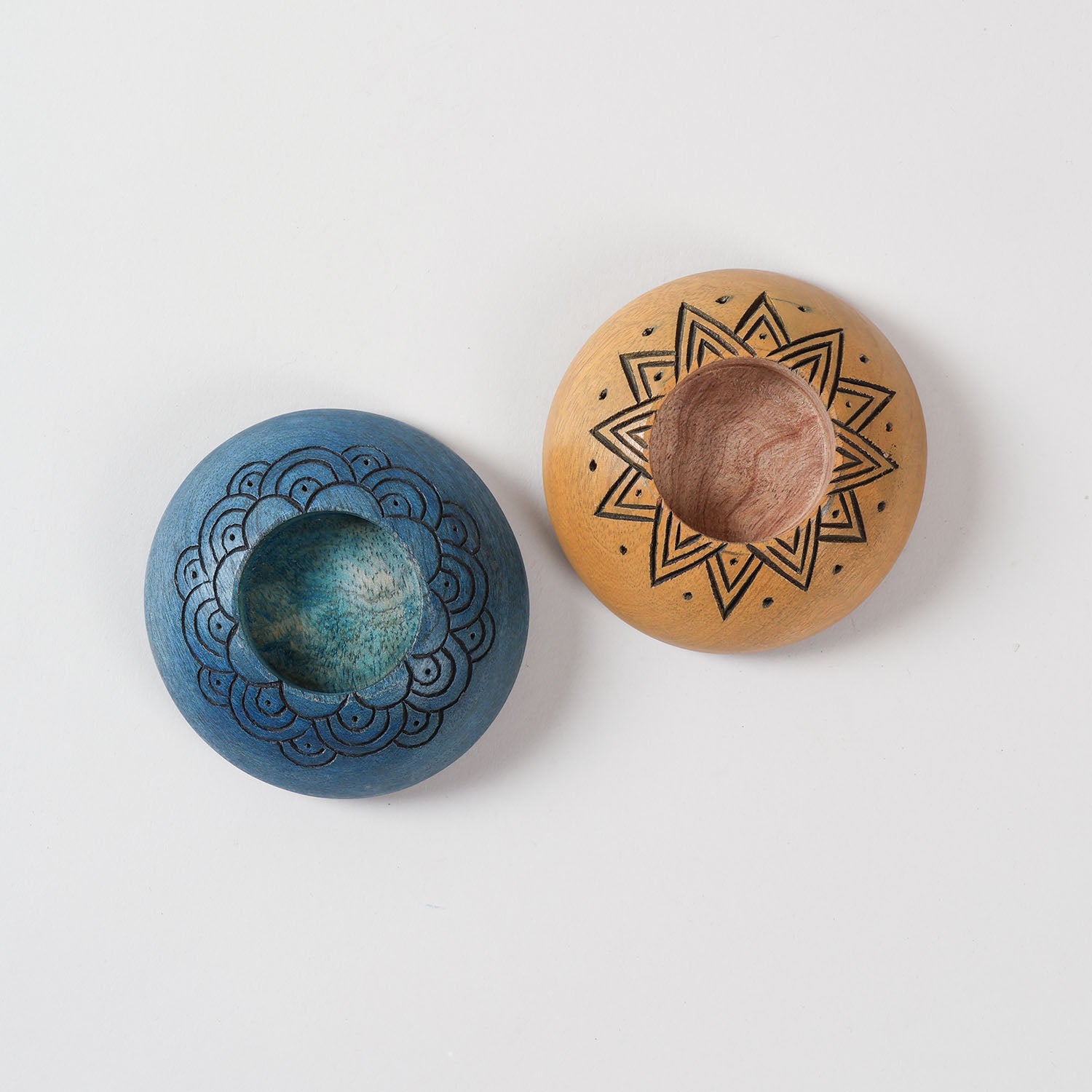  Top view of handcarved wooden T-light holders in blue and yellow, highlighting detailed carving patterns and candle holder design