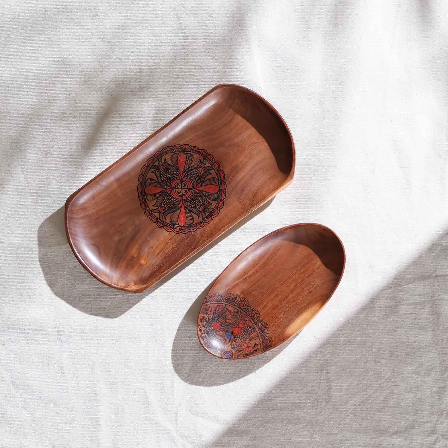 Two wooden trays with decorative fish paintings on a light fabric background