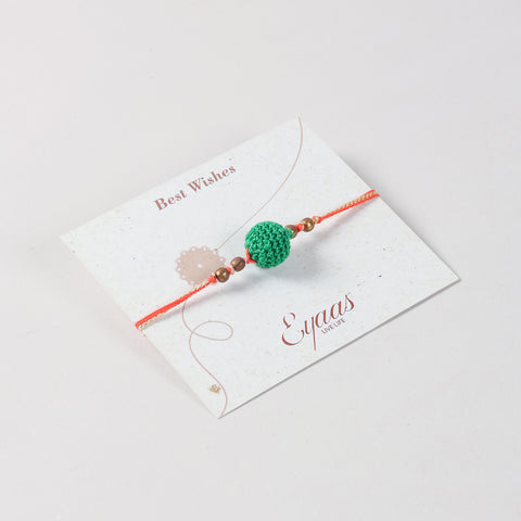 Angled view of the Handmade Crochet Bead Rakhi in Green attached to a festive Best Wishes card for Raksha Bandhan gifting.