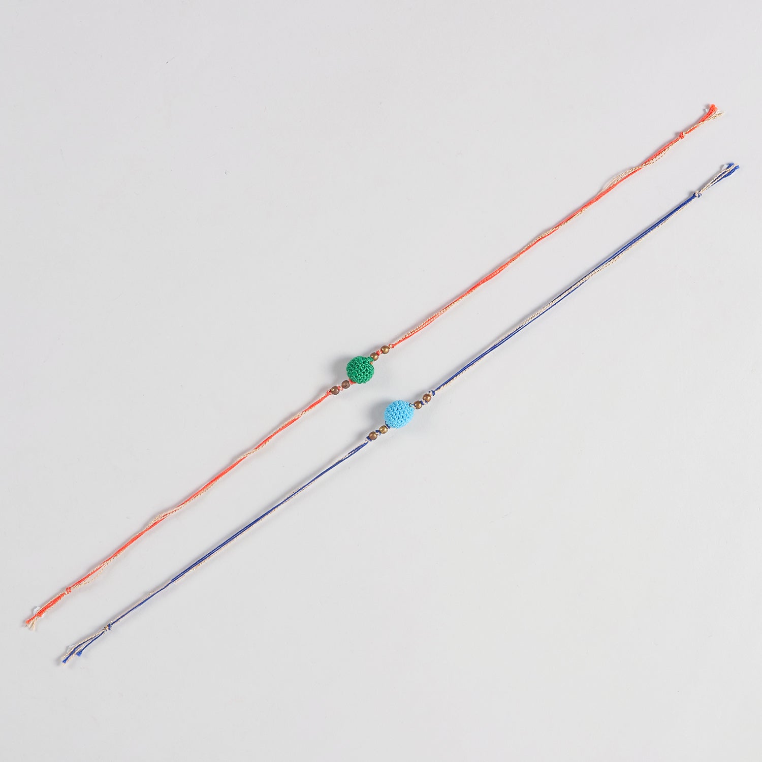 Full-length view of the Handmade Crochet Bead Rakhi showing the complete dual-colour cotton threads and handcrafted crochet bead design