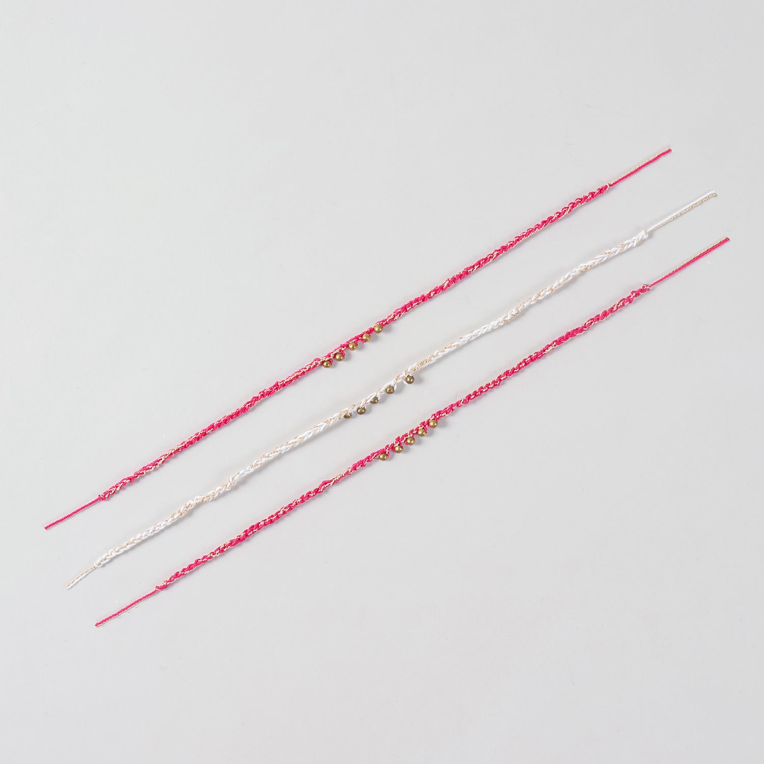 Full-length view of the Handmade Crochet Brass Bead Rakhi showing the complete braided cotton thread and handcrafted brass bead design.
