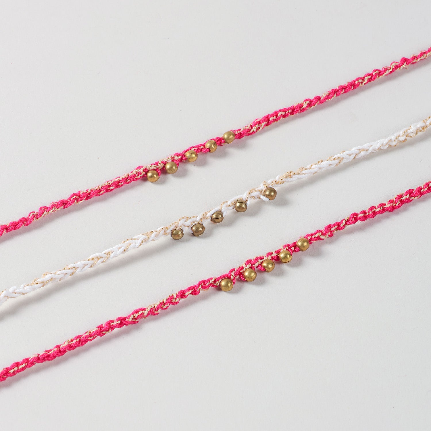 Close-up of the Handmade Crochet Brass Bead Thread Rakhi highlighting the hand-crocheted cotton threads, brass beads, and gold thread detailing