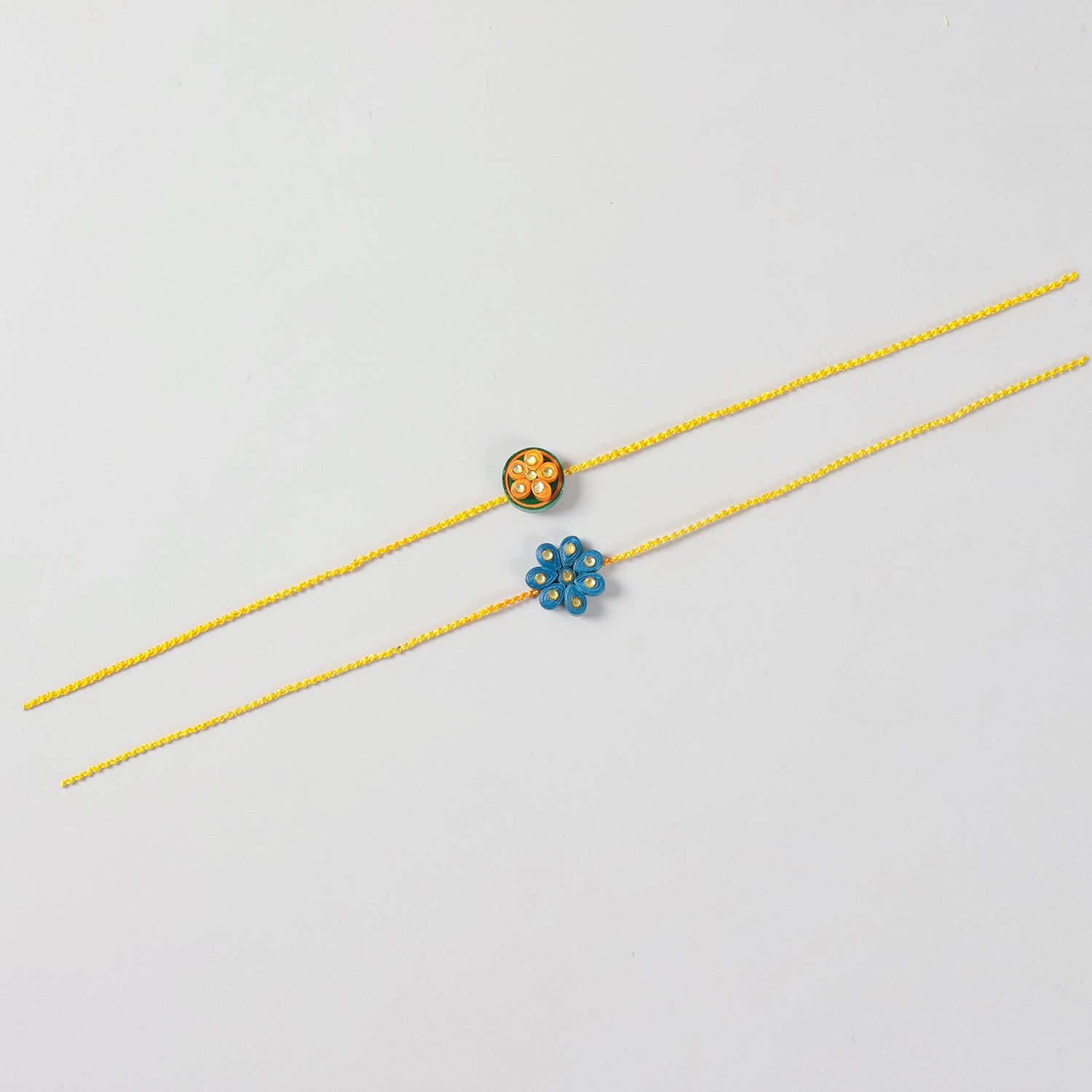 Full-length view of the Handmade Floral Paper Quilled Rakhi showing the handcrafted floral motif and cotton thread.