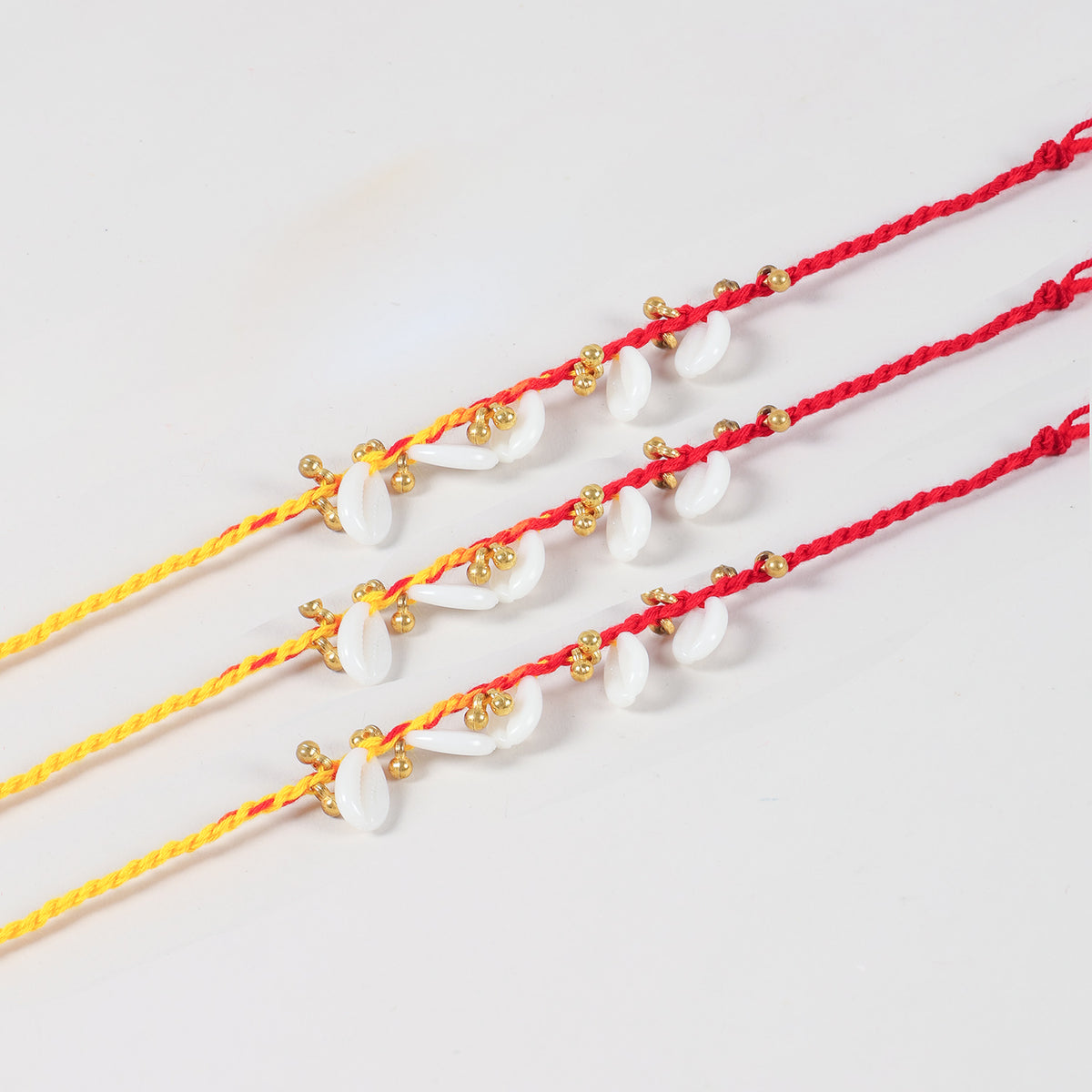 Close-up of the Handmade Kaudi & Ghungroo Rakhi featuring natural kaudi shells, golden ghungroos, and Mauli thread