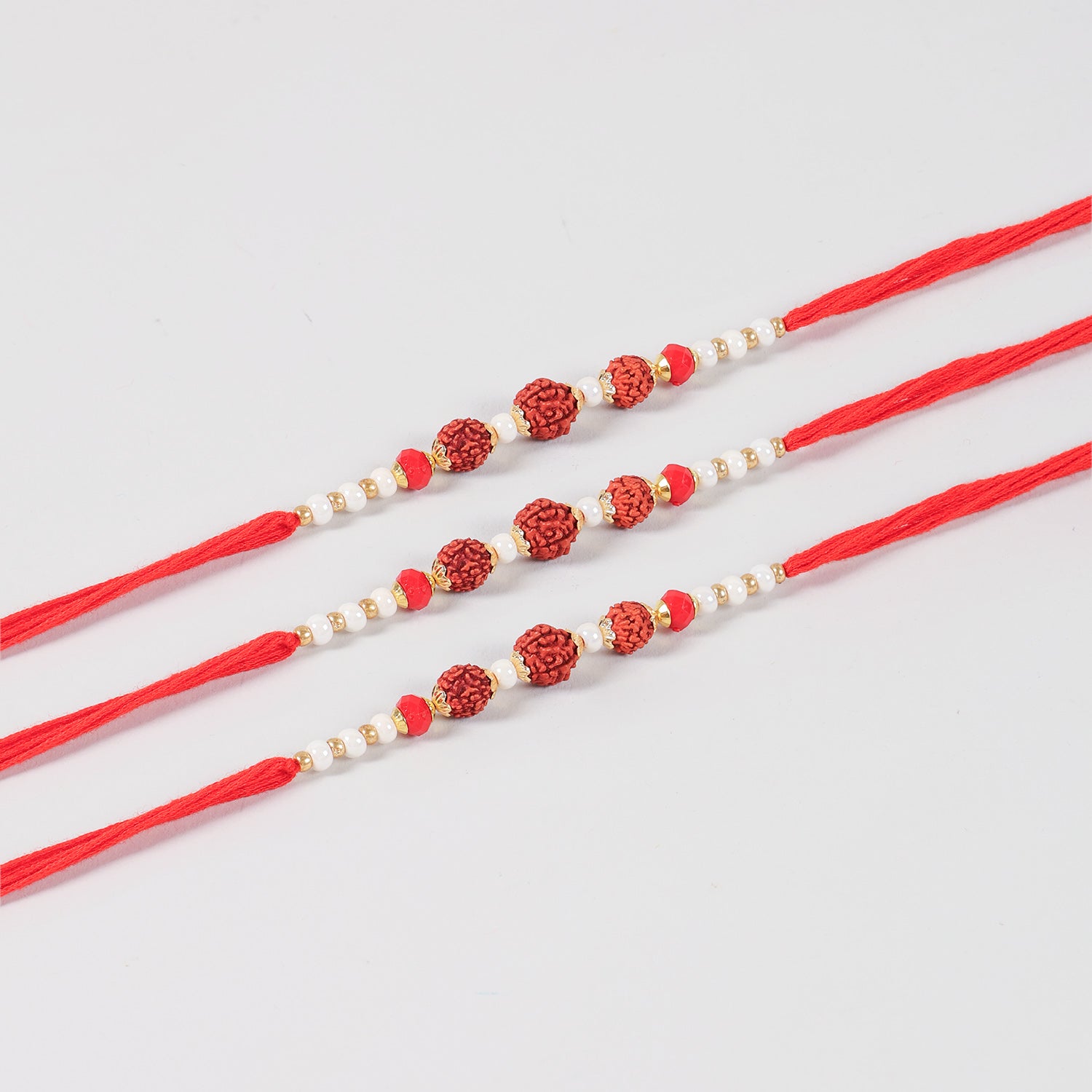 Close-up of the Handmade Rudraksha Rakhi featuring natural Rudraksha beads, white pearls, red beads, and gold-toned decorative accents.