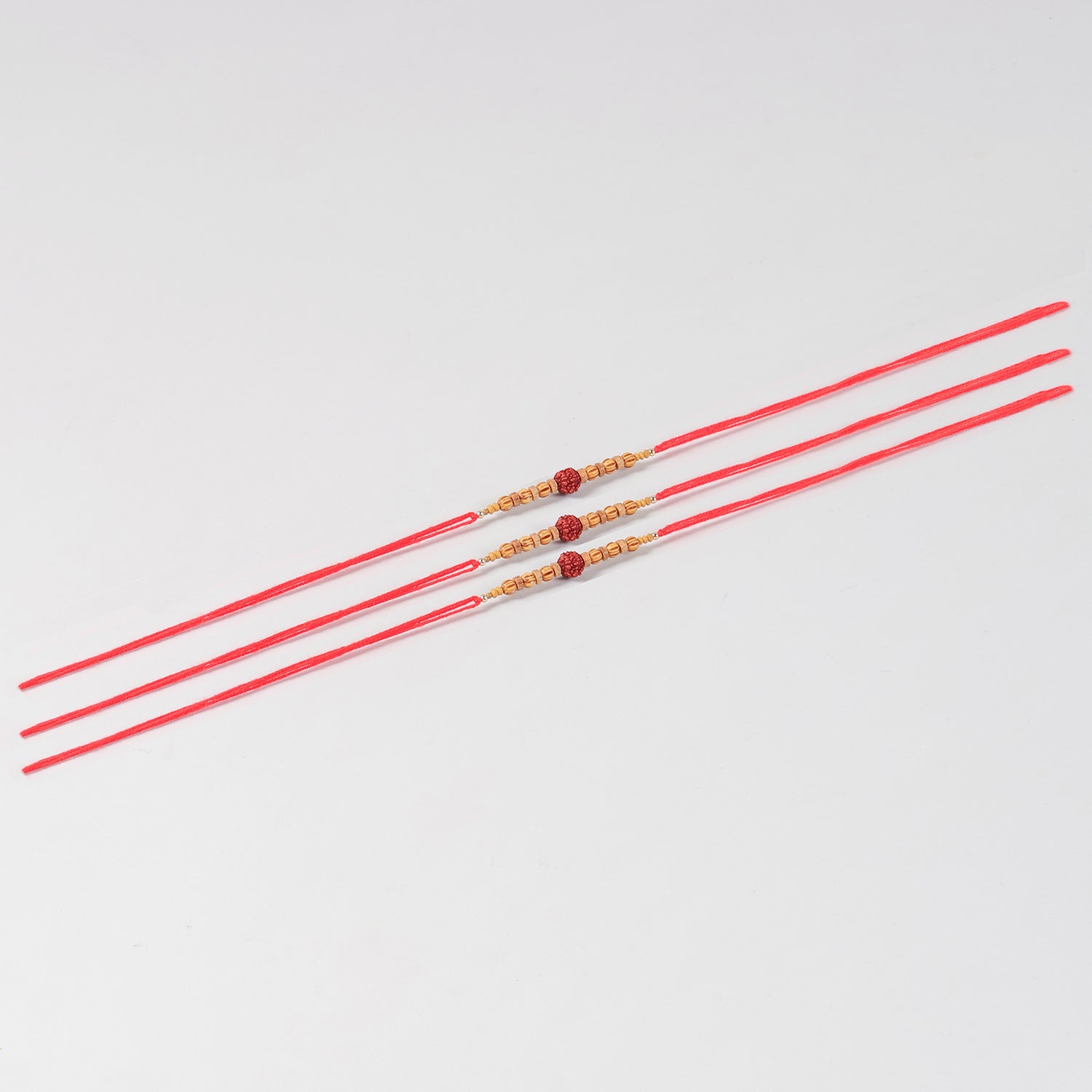 Full-length view of the Handmade Rudraksha & Wooden Bead Rakhi Set of 3 with handcrafted beadwork and Mauli red thread.