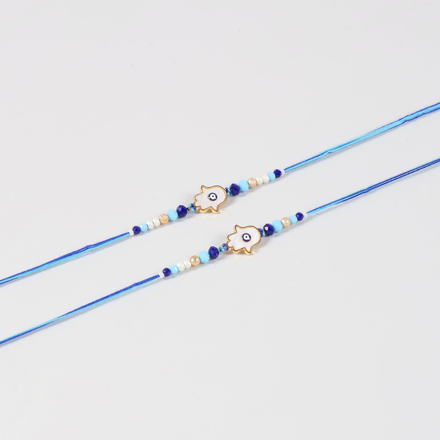 Close-up of the Handmade White Hamsa Evil Eye Rakhi featuring the white Hamsa charm, blue Evil Eye, and handcrafted beadwork.