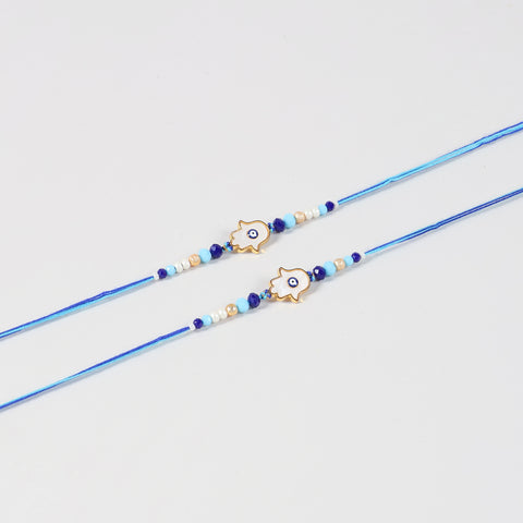Close-up of the Handmade White Hamsa Evil Eye Rakhi featuring the white Hamsa charm, blue Evil Eye, and handcrafted beadwork.