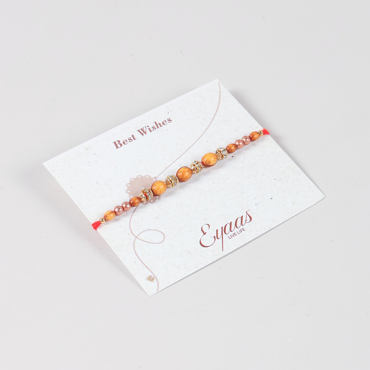 Angled view of the Handmade Wooden & Glass Beads Rakhi attached to a Best Wishes greeting card for Raksha Bandhan