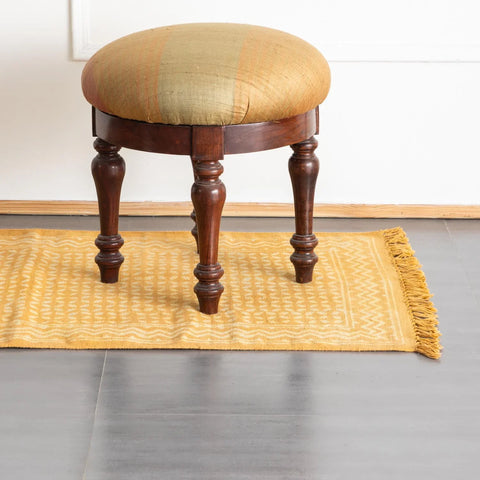 Handwoven cotton rug in mustard with geometric block print design styled on the floor for living room decoration