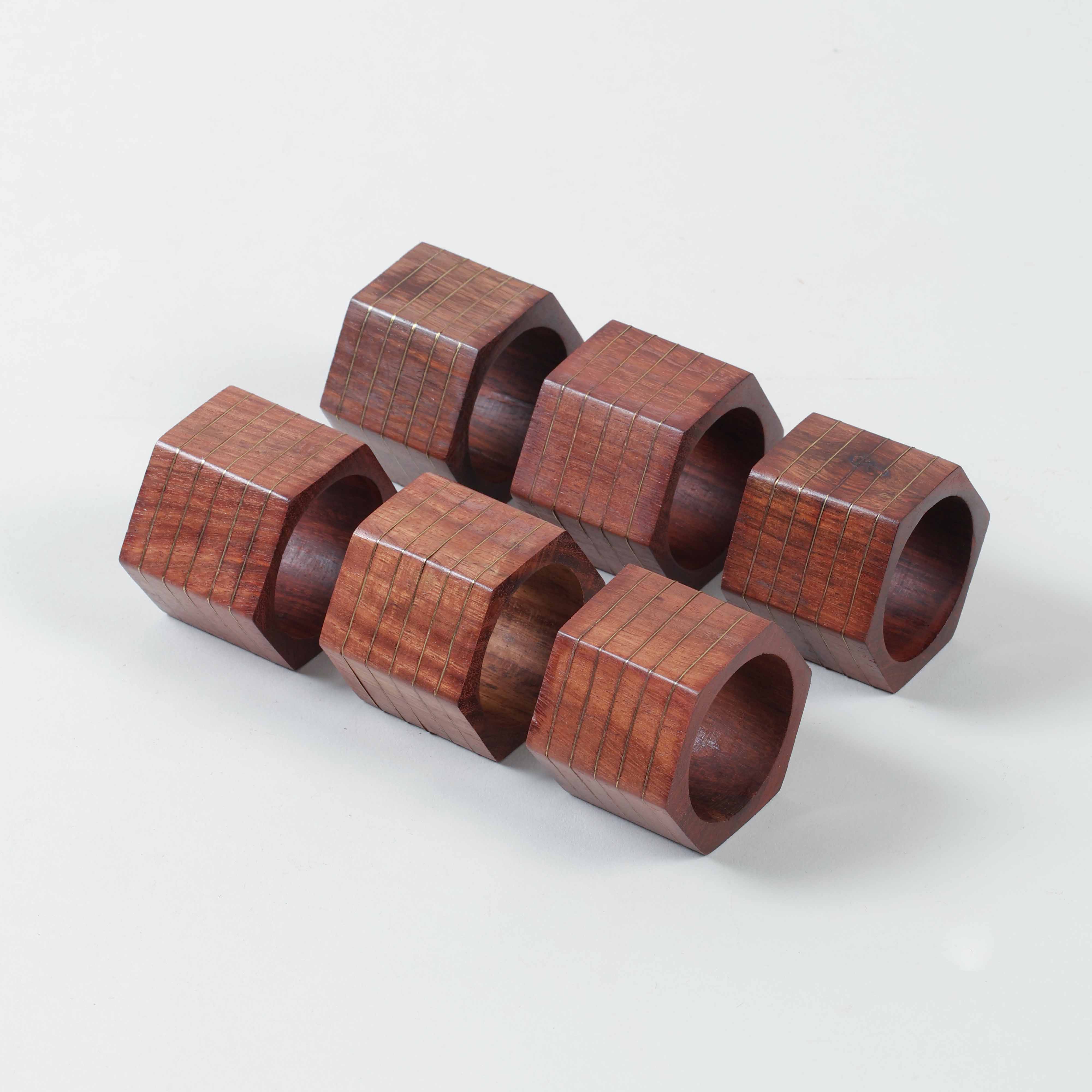 Set of six hexagon wooden napkin rings featuring striped brass inlay and handcrafted geometric design