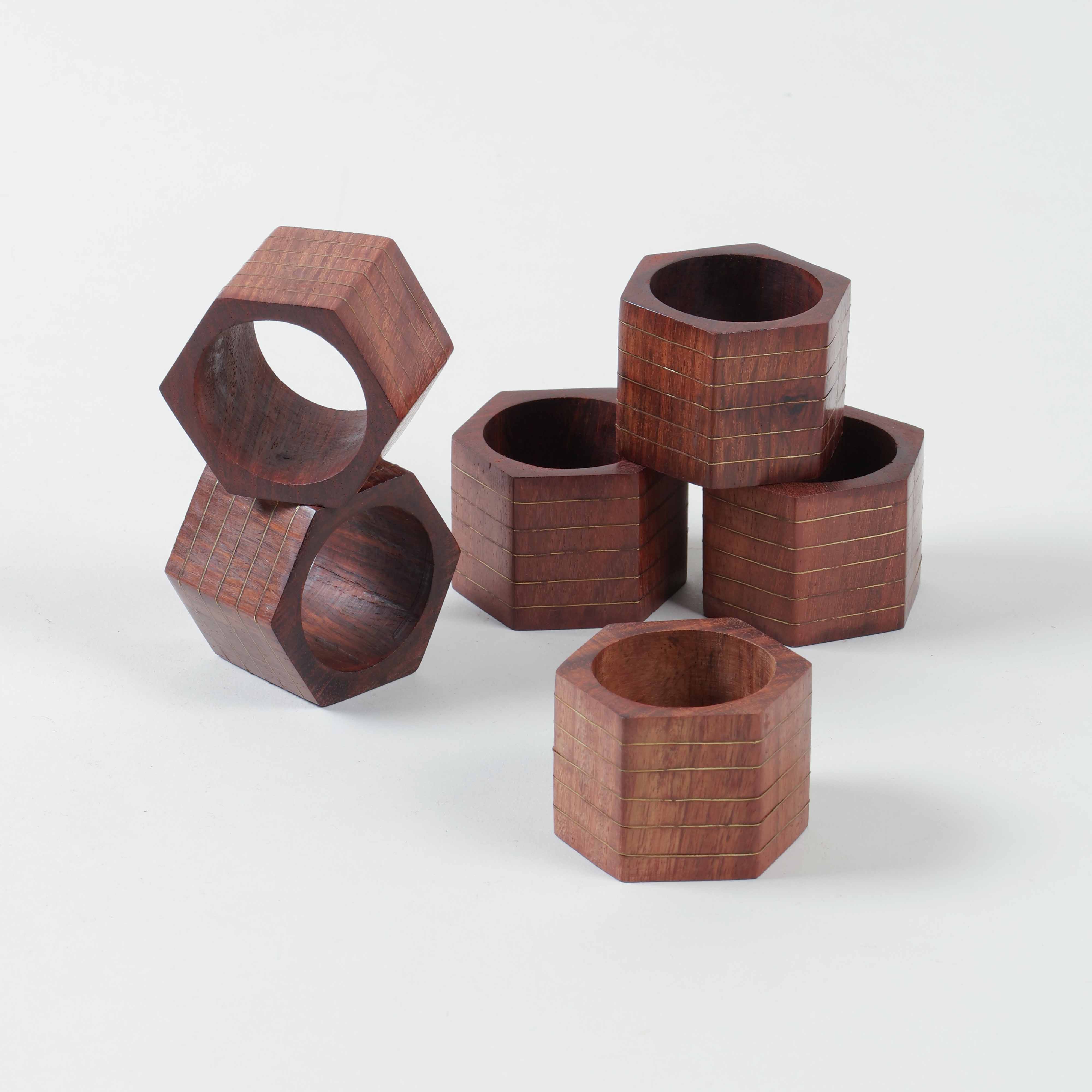Side view of stacked six hexagon wooden napkin rings showcasing angular form and brass inlay detailing