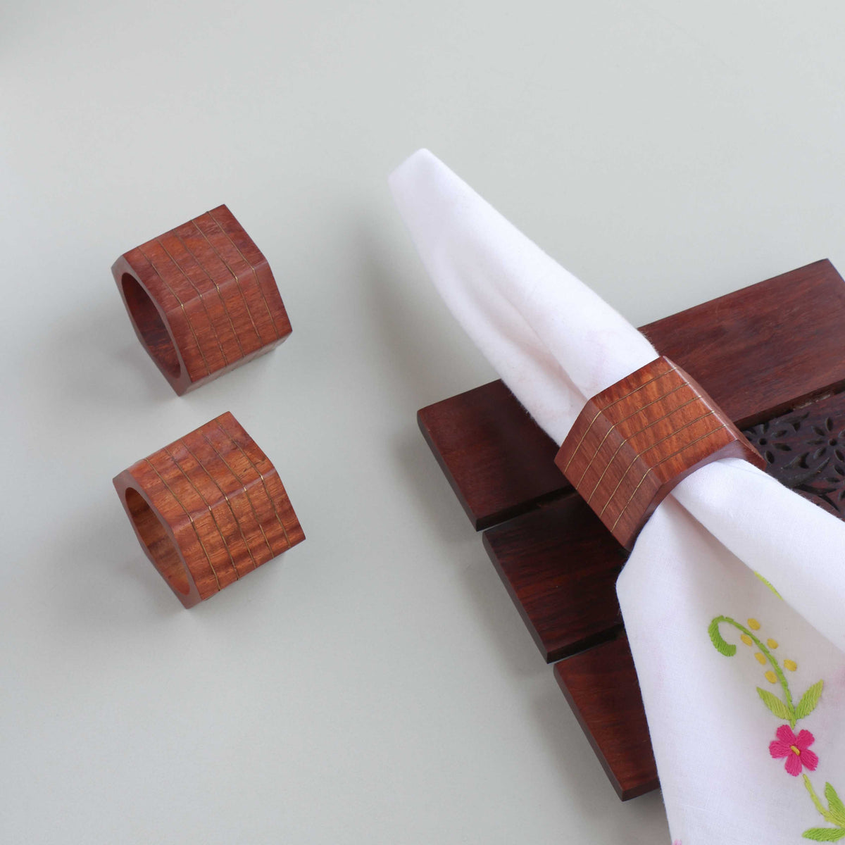 Hexagon wooden napkin rings with striped brass inlay styled on a dining table for elegant table setting decor