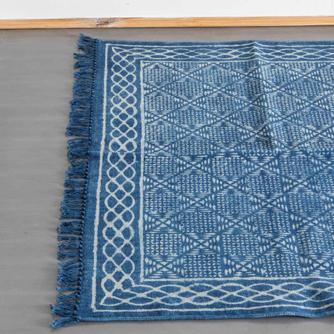 Top view of an indigo cotton dhurrie rug highlighting geometric hand block printed motifs and woven fringe detailing