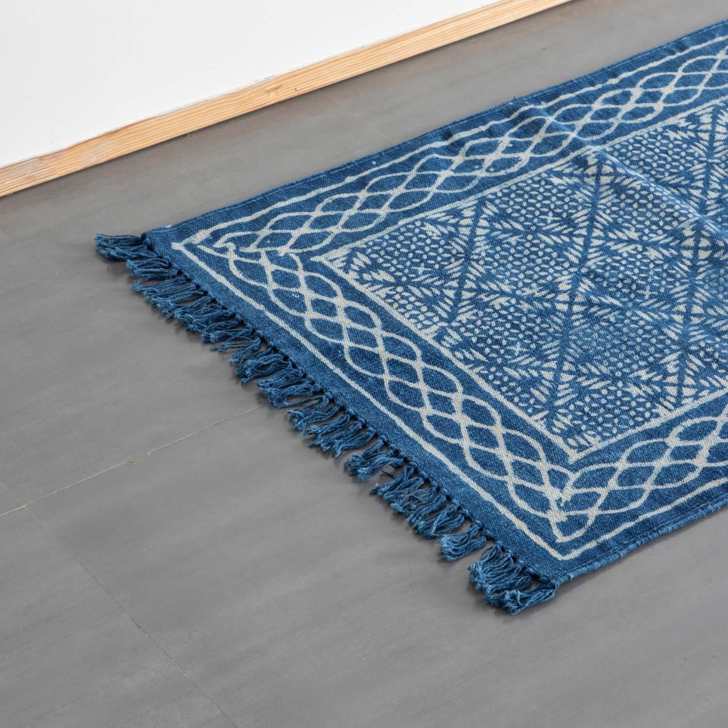 Angled view of a styled geometric indigo block printed dhurrie rug handcrafted in cotton