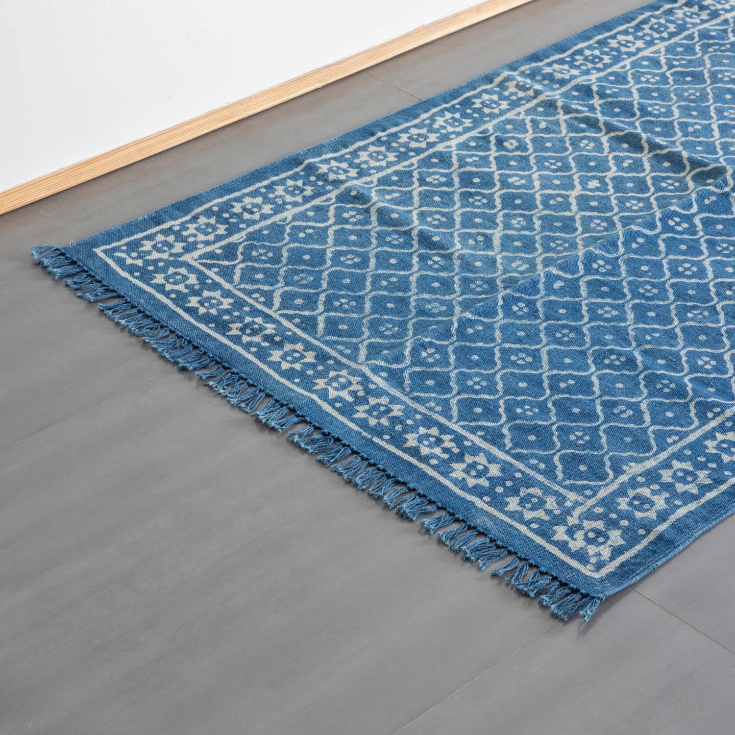 Oblique high-angle view of an indigo diamond floral block printed dhurrie rug showcasing pattern layout and craftsmanship