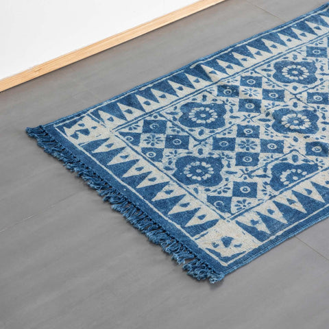 Angled view of a handmade indigo geometric floral cotton dhurrie